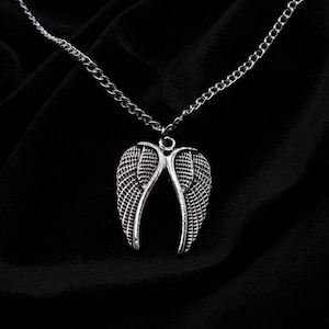 May include: A silver chain necklace with a pendant shaped like a pair of angel wings.