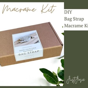 Puede incluir: Una caja de cartón marrón con una etiqueta blanca que dice "Make Your Own Macrame Bag Strap". La caja está sentada en una mesa con una planta verde en el fondo. La etiqueta también tiene una imagen de una correa de bolso de macramé.
