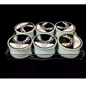 May include: Six spools of 100-yard, 10-pound Dacron braided trolling and surfing line. The spools are white with black labels and gold accents. The labels read "Dacron Braided Trolling & Surfing Line 100 Yards 10 LB."