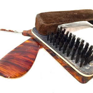 Op de afbeelding: Een vintage schoenlepel- en borstelset van schildpad met een bruine suède borstel en een schildpadsteel.