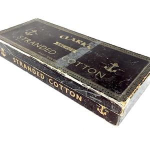 May include: A vintage box of Clark's Anchor Stranded Cotton thread. The box is black with gold lettering and an anchor symbol. The text on the box reads "Clark's Anchor Stranded Cotton Fast Color."
