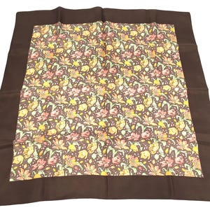 May include: A brown silk scarf with a floral pattern in shades of yellow, pink, and green. The scarf has a brown border.