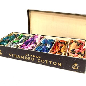 May include: A black box filled with colorful spools of Clark's Stranded Cotton thread. The box has a gold anchor logo and the text "Clark's Stranded Cotton".