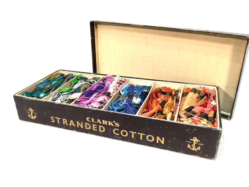 May include: A black box filled with colorful spools of Clark's Stranded Cotton thread. The box has a gold anchor logo and the text "Clark's Stranded Cotton".