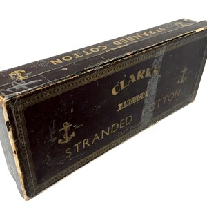 May include: A vintage box of Clark's Anchor Stranded Cotton. The box is brown with gold lettering and an anchor logo. The text on the box reads "Clark's Anchor Stranded Cotton Fast Color."