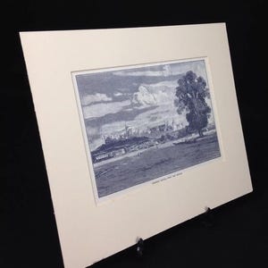 May include: A black and white print of a city skyline with a large tree in the foreground. The print is framed in a white mount and has the text "Windsor Castle from the South" at the bottom.