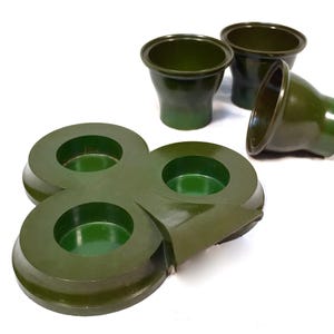 Può includere: Un set di quattro portacandele in ceramica verde. Tre dei portacandele sono coppe individuali e uno è un portacandele a tre coppe.