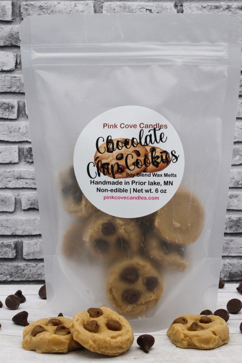 May include: A clear plastic bag filled with chocolate chip cookie wax melts. The bag has a white label with the text "Pink Cove Candles Chocolate Chip Cookies Soy Blend Wax Melts Handmade in Prior Lake, MN Non-edible | Net wt. 6 oz pinkcovecandles.com".