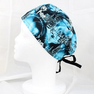 May include: A blue and black scrub hat with a Harry Potter design. The hat has a tie at the back.