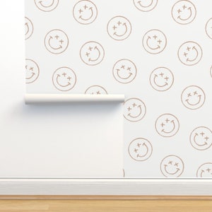 May include: A white background with a repeating pattern of brown smiley faces. Each smiley face has two plus signs above the eyes and a curved line for a mouth.