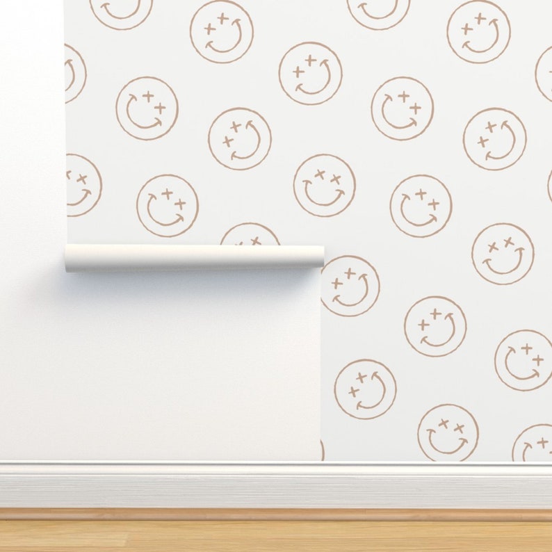 May include: A white background with a repeating pattern of brown smiley faces. Each smiley face has two plus signs above the eyes and a curved line for a mouth.