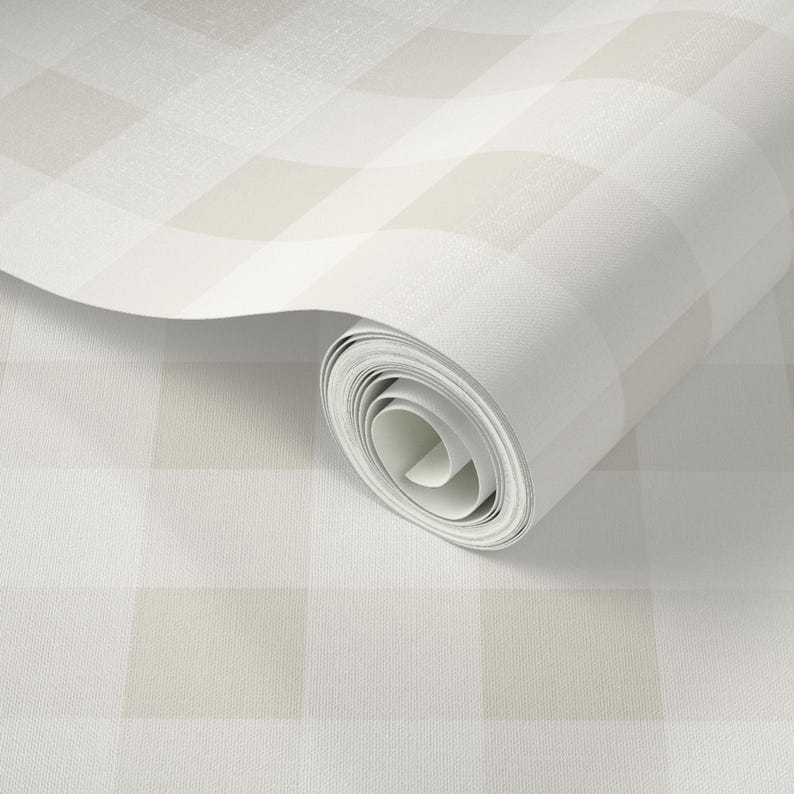 Puede incluir: Un rollo de papel tapiz con un patr&oacute;n de cuadros grandes en tonos suaves de beige y blanco. El material tiene un acabado de superficie sutil y finamente texturizado, y el papel est&aacute; parcialmente desenrollado para mostrar el dise&ntilde;o.