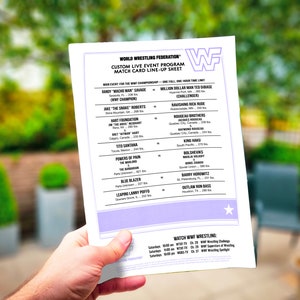 May include: A hand holds a white WWF wrestling event program. The program lists match-ups including "Macho Man" Savage vs. Million Dollar Man, and Jake "The Snake" Roberts. The program also includes a TV schedule for WWF wrestling.
