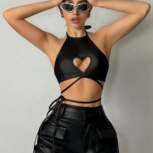 May include: Black halter top with a heart-shaped cutout and wrap-around ties. The top is paired with black leather pants. The outfit is a stylish ensemble.