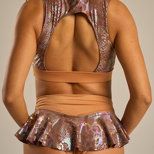 May include: A two-piece dance outfit in a snakeskin pattern. The top is a crop top with a keyhole back. The skirt is a ruffled mini skirt. The outfit is a metallic bronze color with iridescent highlights.