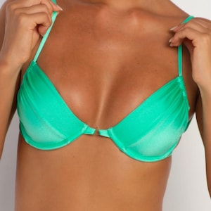 May include: A bright green bikini top with adjustable straps and a clasp closure. The fabric has a slight sheen, and the design features a gathered detail at the bust. The top is part of a swimwear set.