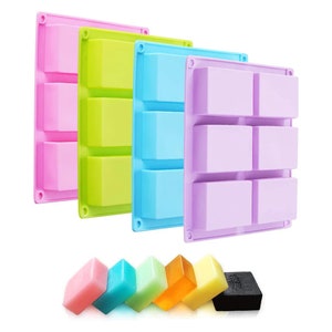 Pode incluir: Três moldes de sabão de silicone em rosa, verde e azul, cada um com seis cavidades retangulares. Os moldes são mostrados ao lado de sete barras de sabão de várias cores, incluindo rosa, azul, verde, amarelo e preto.