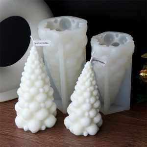 May include: Two white silicone moulds for making scented candles in the shape of a Christmas tree. The moulds are labelled "Scented candles".