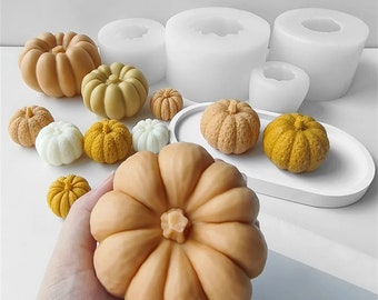 Peut inclure: Un ensemble de moules en silicone pour la fabrication de bougies ou de savon en forme de citrouille. Les moules sont blancs et sont présentés avec plusieurs citrouilles finies de différentes tailles et couleurs.