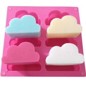 May include: Pink silicone mold with four cloud-shaped cavities. The mold is filled with four different colored soaps: light blue, yellow, pink, and white.