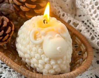 May include: A white sheep-shaped candle with a lit wick in the center. The candle is sitting in a woven basket.