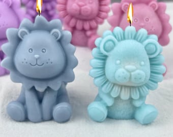 May include: A set of five lion-shaped candles, each with a different color. The candles are blue, light blue, purple, pink, and white. The candles are all sitting on a white surface.
