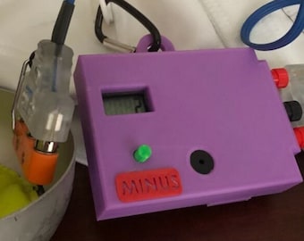 May include: A purple electronic device with a digital display and a red button labeled "MINUS". The device is connected to a white cord and a clear plastic component with red and black wires.