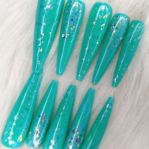 May include: Set of ten turquoise long false nails with iridescent glitter embedded in the polish.