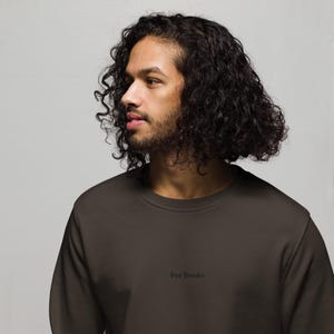 May include: A dark brown sweatshirt with the text "For Frodo" in a small, centered font. The sweatshirt is a solid color and appears to be made of a soft material. The person wearing the sweatshirt has dark curly hair and a beard.