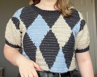 May include: A short-sleeved crocheted sweater with a diamond pattern in black, beige, and light blue.