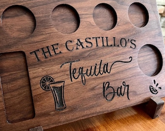 May include: A wooden serving tray with five shot glass holders, a small compartment, and a stand. The tray is engraved with the text "The Castillo's Tequila Bar" and a lime wedge and margarita glass graphic.