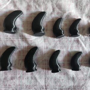 May include: Ten black plastic horns of varying sizes. The horns are all pointed and have a smooth, glossy finish.
