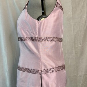 May include: Pale pink sleeveless top with a V-neckline. The top is embellished with rows of dark brown beading. The fabric has a subtle sheen. The garment is displayed on a mannequin.