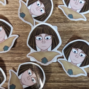 May include: A set of five stickers featuring a cartoon girl with brown hair and a yellow shirt. The girl has a surprised expression on her face. The stickers are printed on white paper and have a glossy finish.