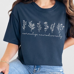 May include: Midnight blue t-shirt featuring a floral design and the words "normalise neurodiversity" in a delicate script. The shirt has a relaxed fit and is made of soft material. The design features several botanical illustrations.