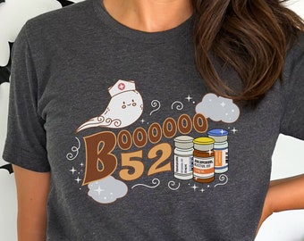 May include: A dark gray t-shirt with a graphic of a ghost wearing a nurse's hat and holding a bottle of B-52. The text "BOO00000 B52" is printed on the shirt.