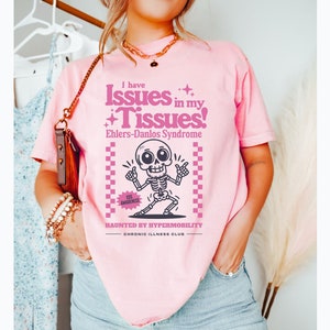 May include: Pink t-shirt with a skeleton graphic and the text "I have Issues in my Tissues! Ehlers-Danlos Syndrome Haunted by Hypermobility Chronic Illness Club".