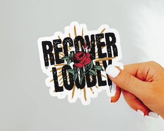 May include: A white sticker with black text that reads "RECOVER LOUDLY" with a red rose and gold accents.