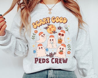 May include: A gray sweatshirt with a graphic print of ghosts wearing nurse hats and the text "Scary Good Peds Crew".