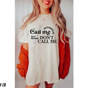 Puede incluir: Una camiseta blanca con el texto "Call me antisocial but please don't call me" en letras negras con estrellas alrededor del texto.