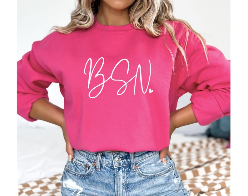 May include: A pink sweatshirt with the text "BSN" in white cursive lettering.