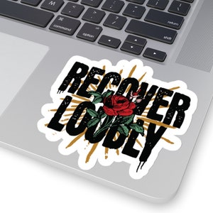 May include: Black and gold sticker with the text "Recover Loudly" in a distressed font. A red rose with green leaves is centred in the sticker.