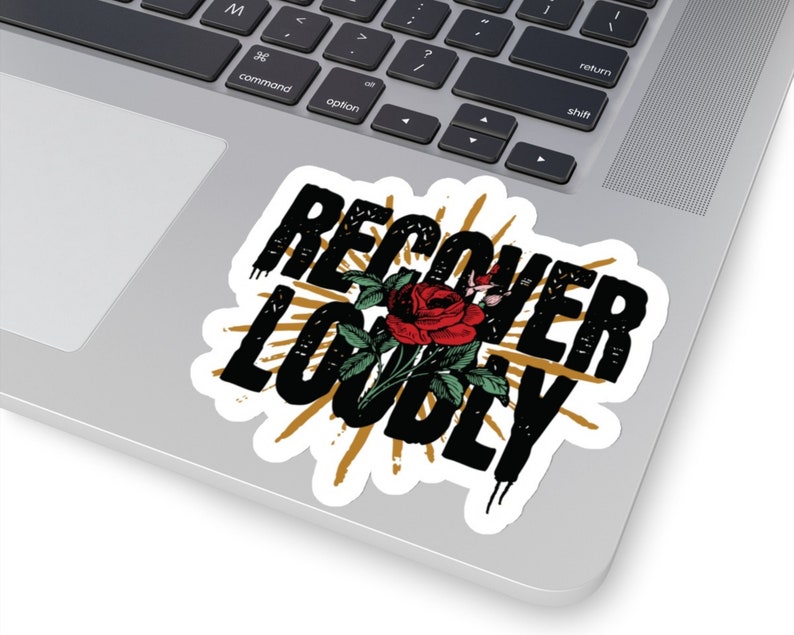 May include: Black and gold sticker with the text "Recover Loudly" in a distressed font. A red rose with green leaves is centred in the sticker.