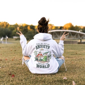 May include: White hoodie with a green, red, and yellow mushroom graphic and the text "Just me and my anxiety against the world".