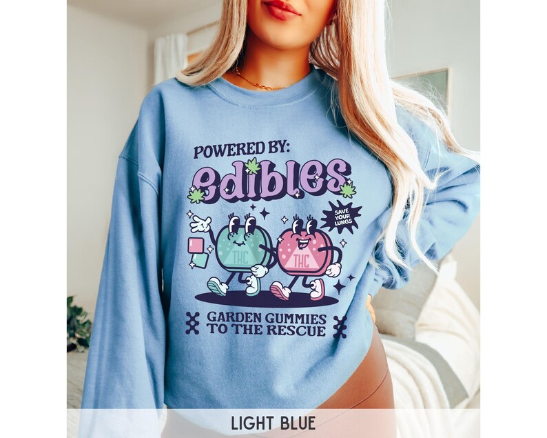 May include: Light blue sweatshirt with a graphic of two cartoon gummies with the text "POWERED BY: edibles" and "GARDEN GUMMIES TO THE RESCUE".