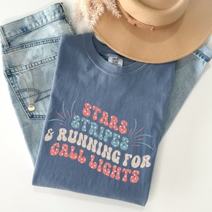May include: A blue t-shirt with a white, red, and blue graphic that says "Stars & Stripes & Running for Call Lights".