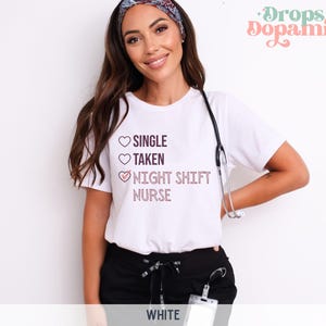 May include: White t-shirt with a pink heart graphic and the text "SINGLE, TAKEN, NIGHT SHIFT NURSE" with a checkmark next to the last option.
