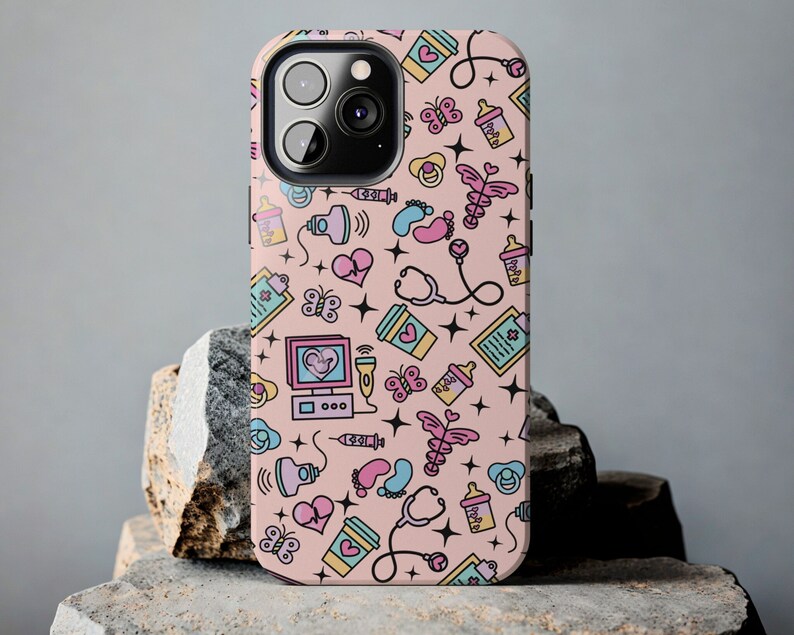 May include: A pink iPhone case with a cute pattern of baby-related icons, including a stethoscope, a baby bottle, a heart, a butterfly, and a baby footprint. The case is designed for an iPhone 13 Pro Max.