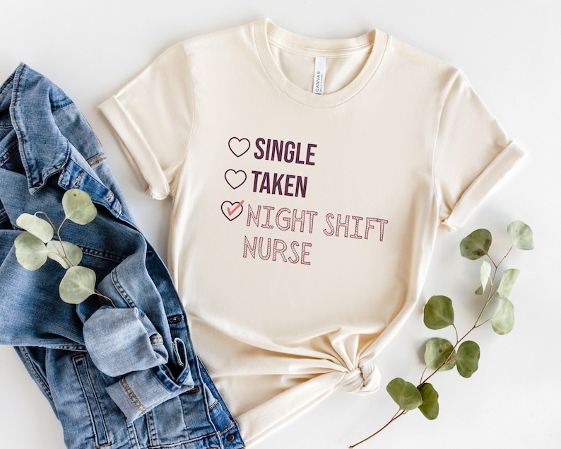 May include: A beige t-shirt with a graphic that says "Single, Taken, Night Shift Nurse" with a checkmark next to the last option.