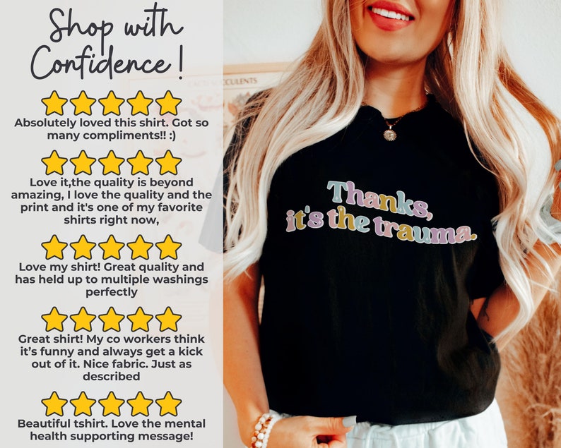 May include: Black t-shirt with the text "Thanks, it's the trauma." in colorful letters. The shirt is being worn by a person with long blonde hair. The shirt has received five-star reviews from customers who praise the quality and design.